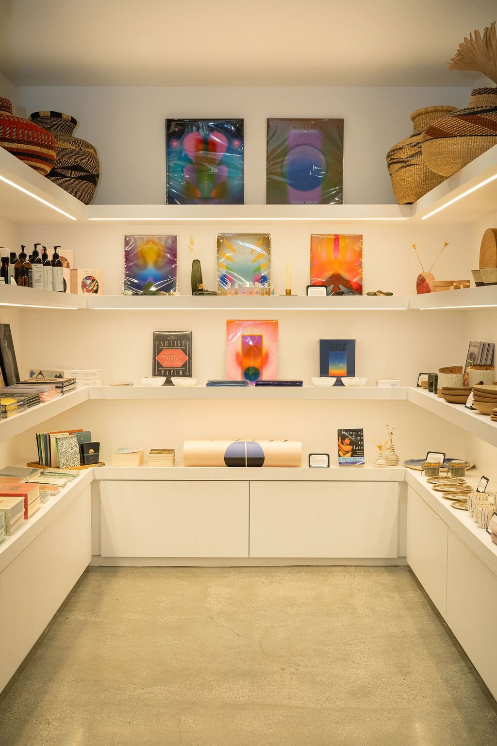 A corner of four underlit white shelves with product displayed