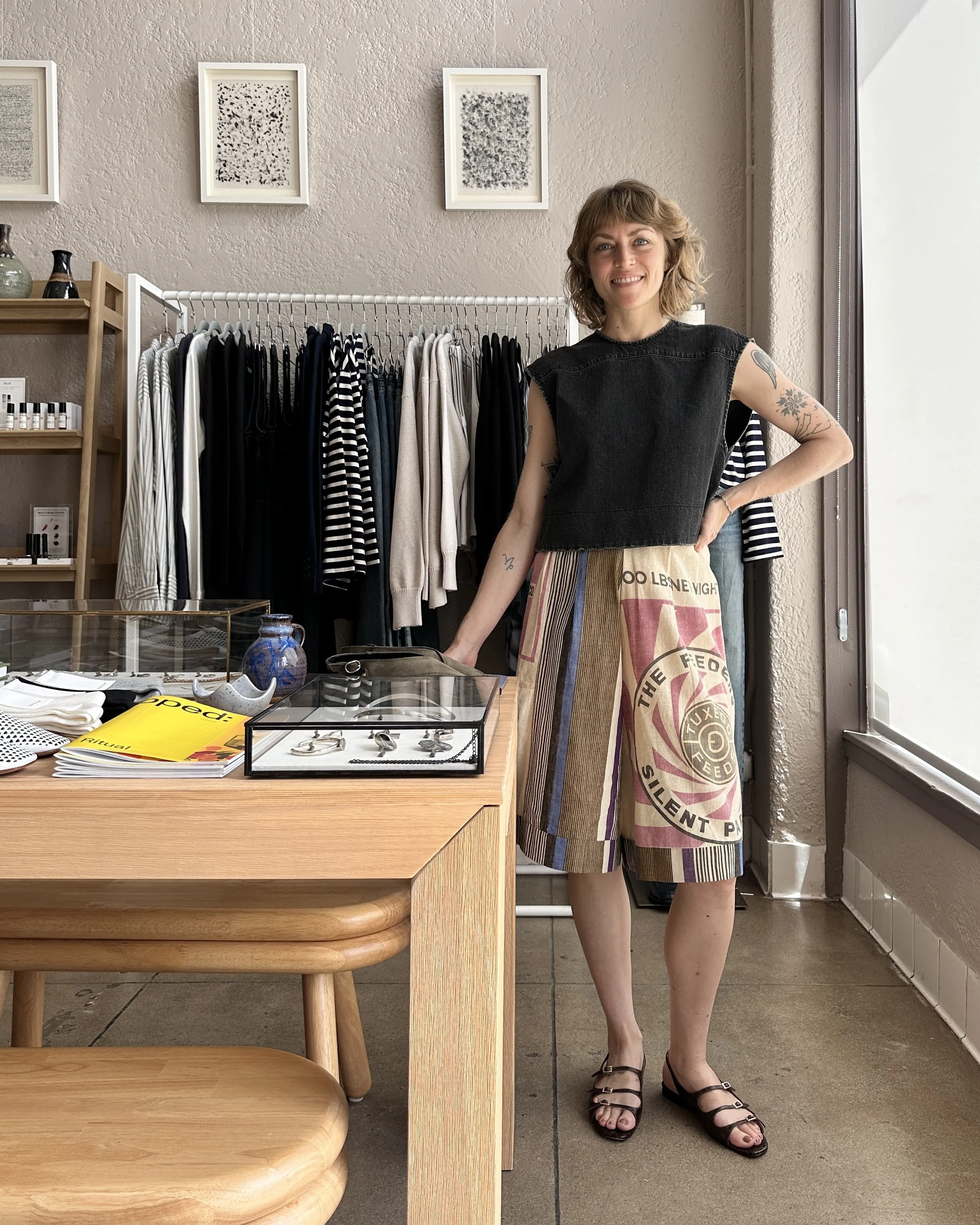 Maggie Stoll standing near a table and clothing rack of merchandise inside the Burke Mercantile shop