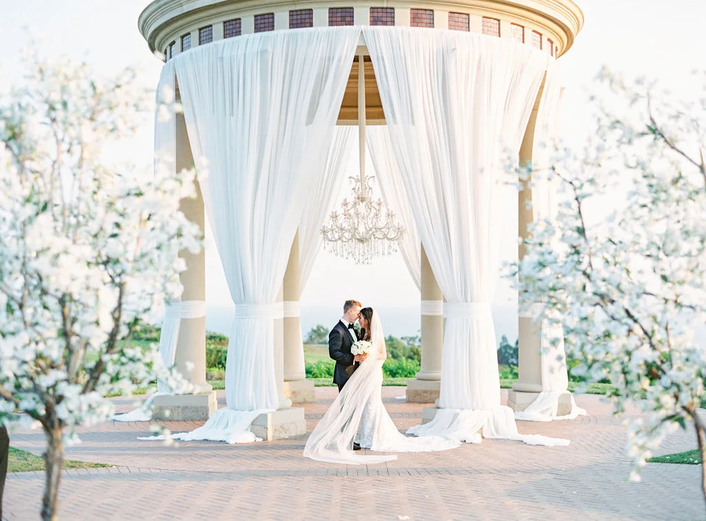 aboutdetailsdetails | cherry blossoms | pelican hill | beach | outdoor ceremony | portraits | kiss | bride and groom | white drapes |