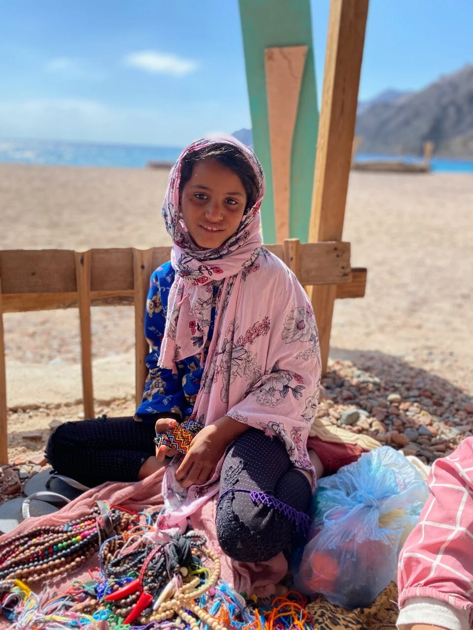 A sweet child selling her bracelets on the beach