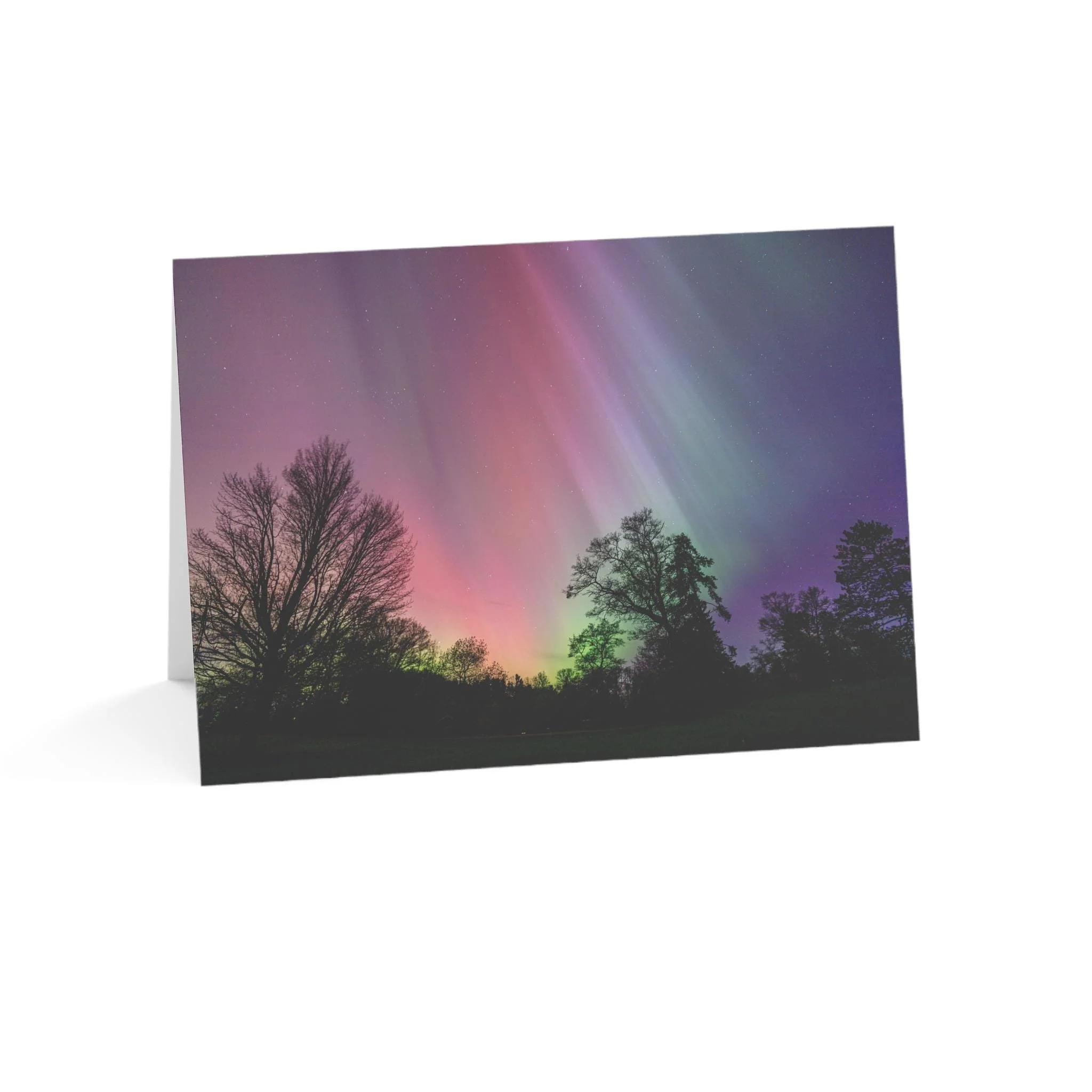A greeting card featuring a photograph of the northern lights in the night sky above trees, with colorful auroras in shades of pink, purple, green, and blue.