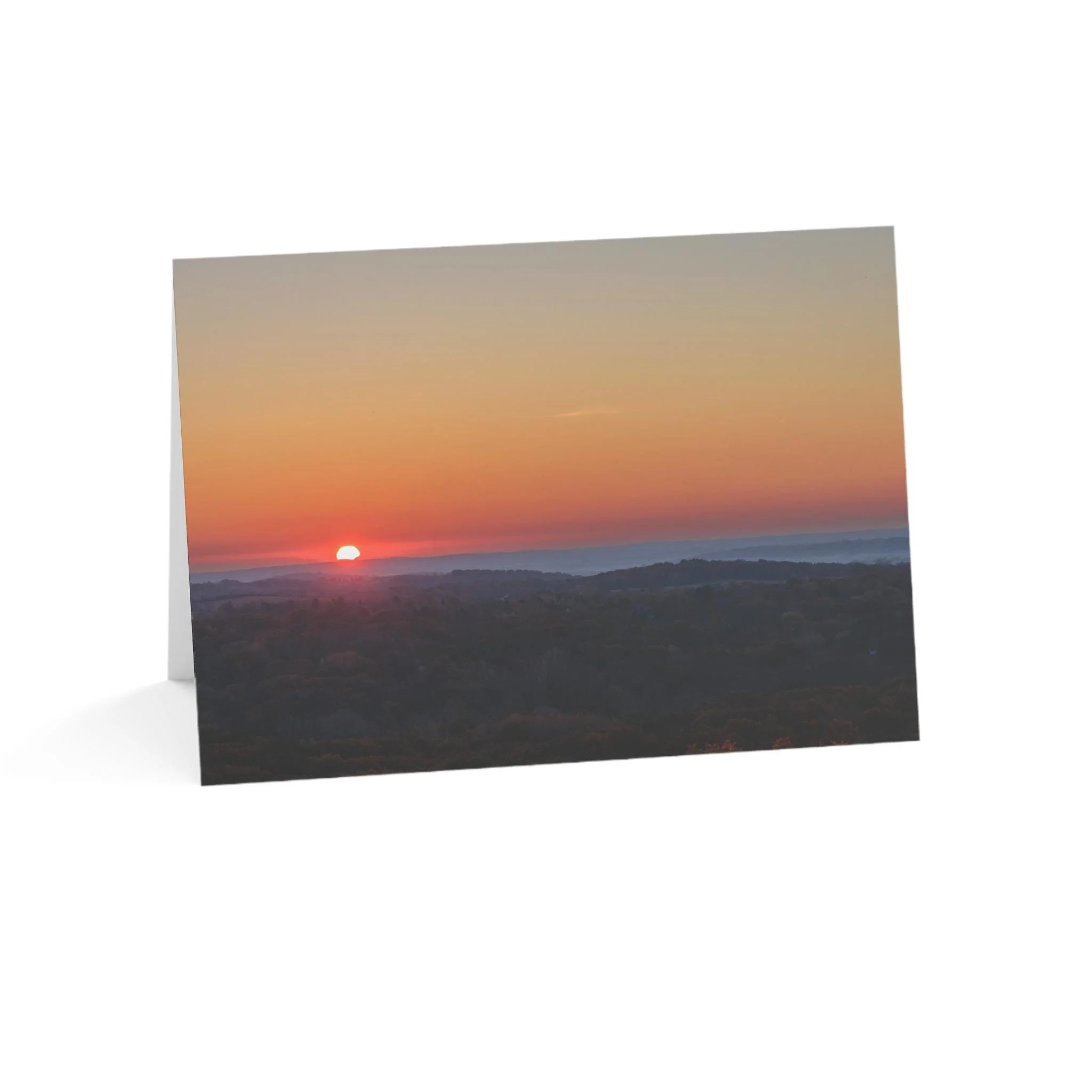 Sunset over a hilly landscape with a colorful sky.