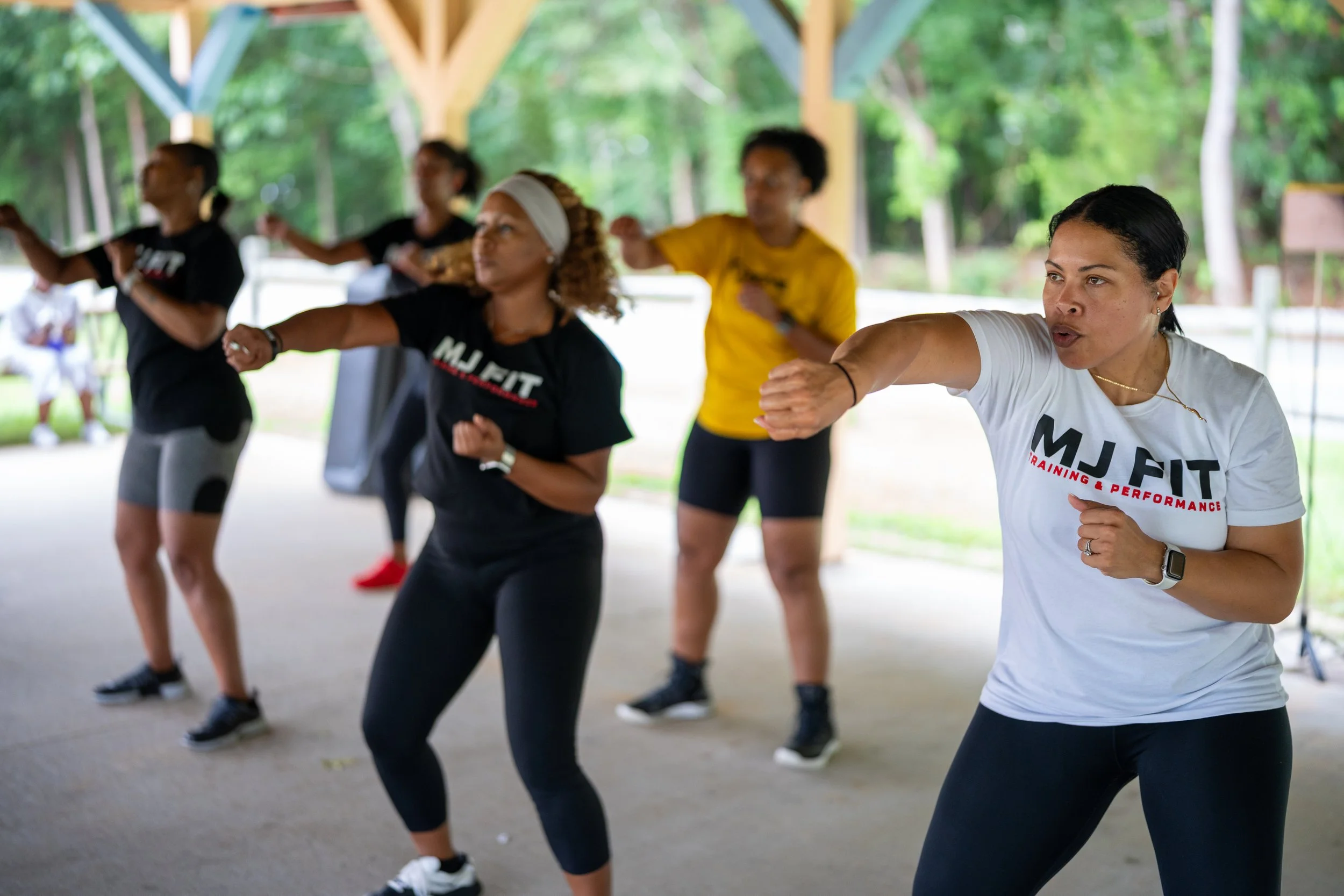MJ Fit Training participants performing a boxing-inspired exercise during an outdoor group fitness class.