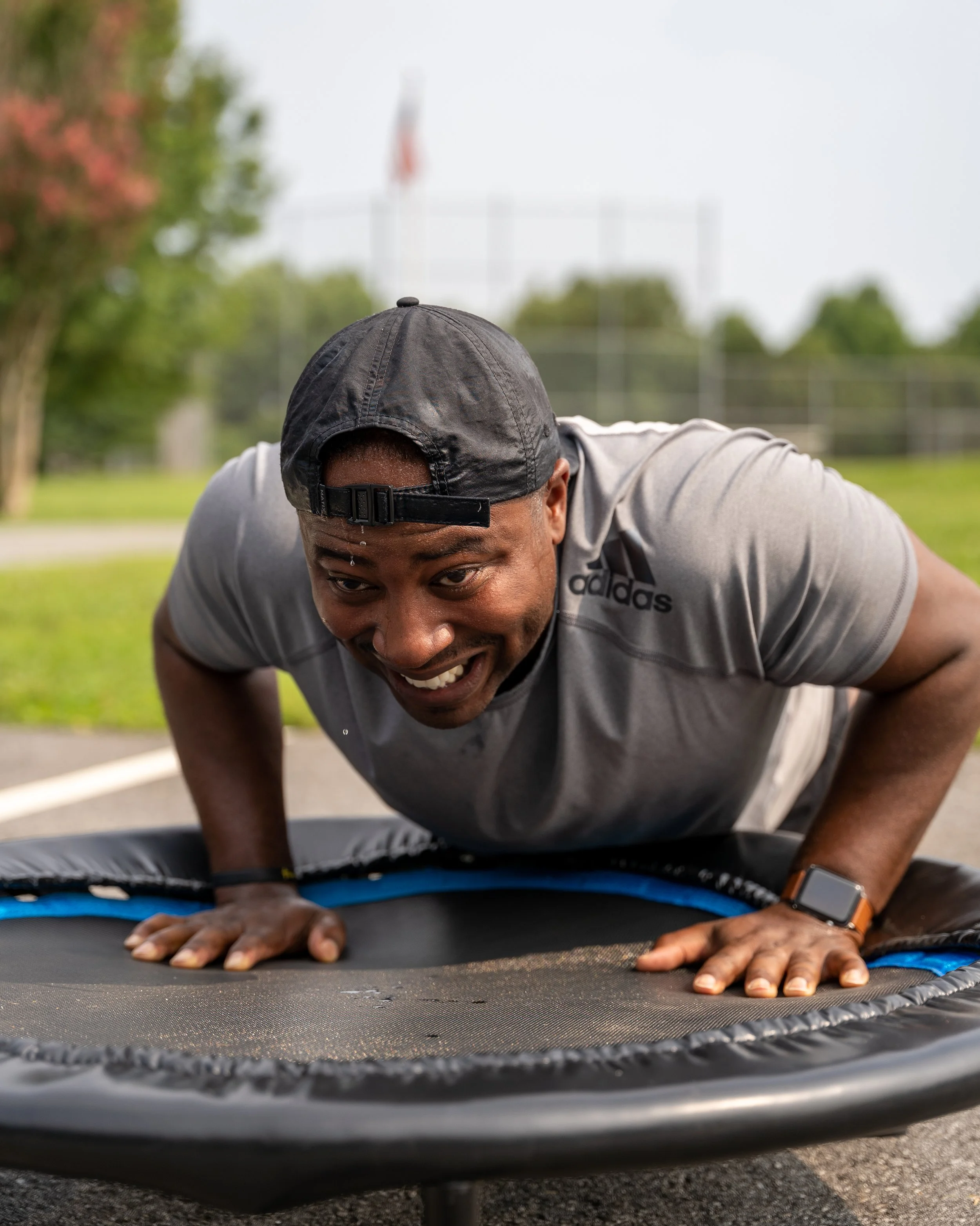 MJ Fit Training participant doing a push-up on a mini trampoline during an outdoor fitness workout.