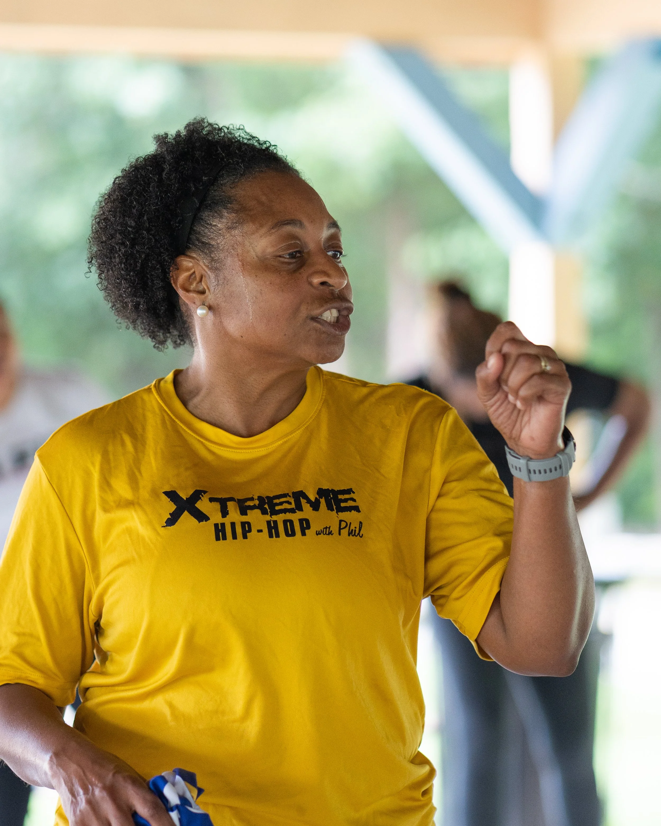 Fitness instructor from Xtreme Hip-Hop with Phil leading an outdoor group workout.