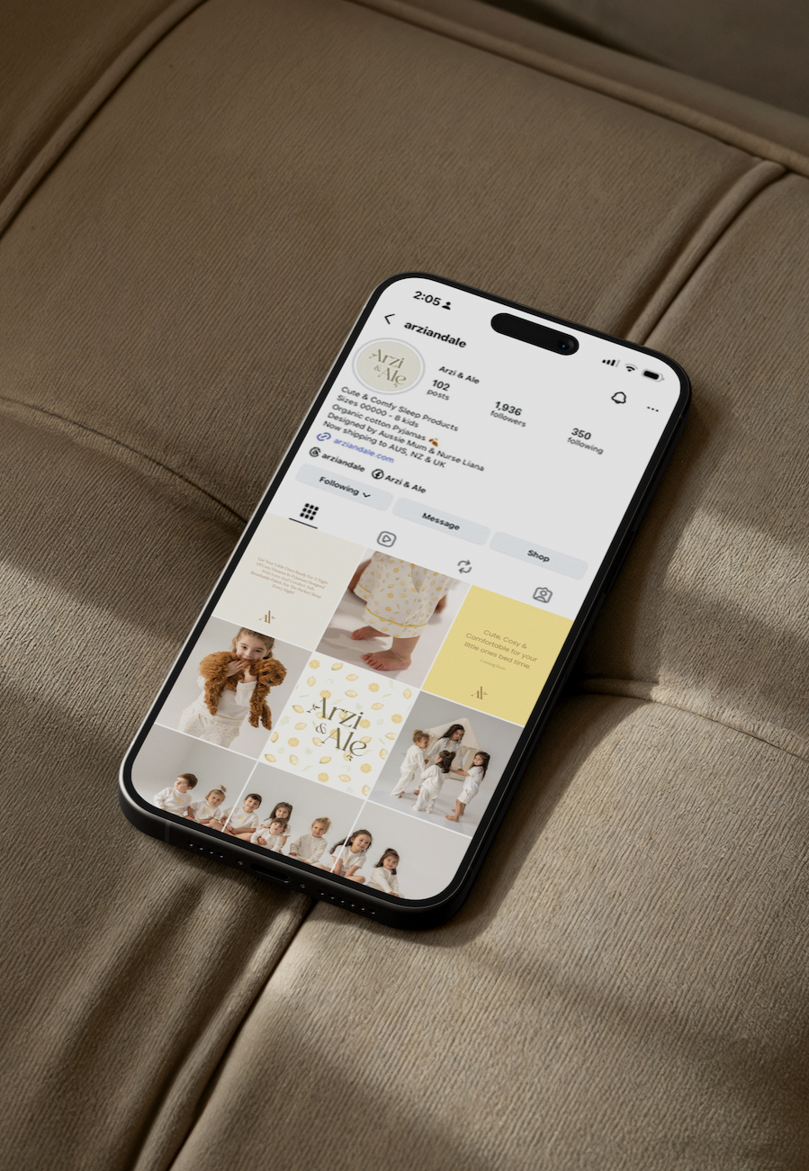 An iPhone displays the social media profile of Arzi & Ale, a brand for cute and cozy sleep products and children's clothing, on a beige upholstered surface.