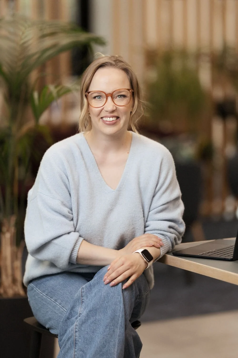 Nainen sinisessä villapaidassa poseeraa pöydän ääressä