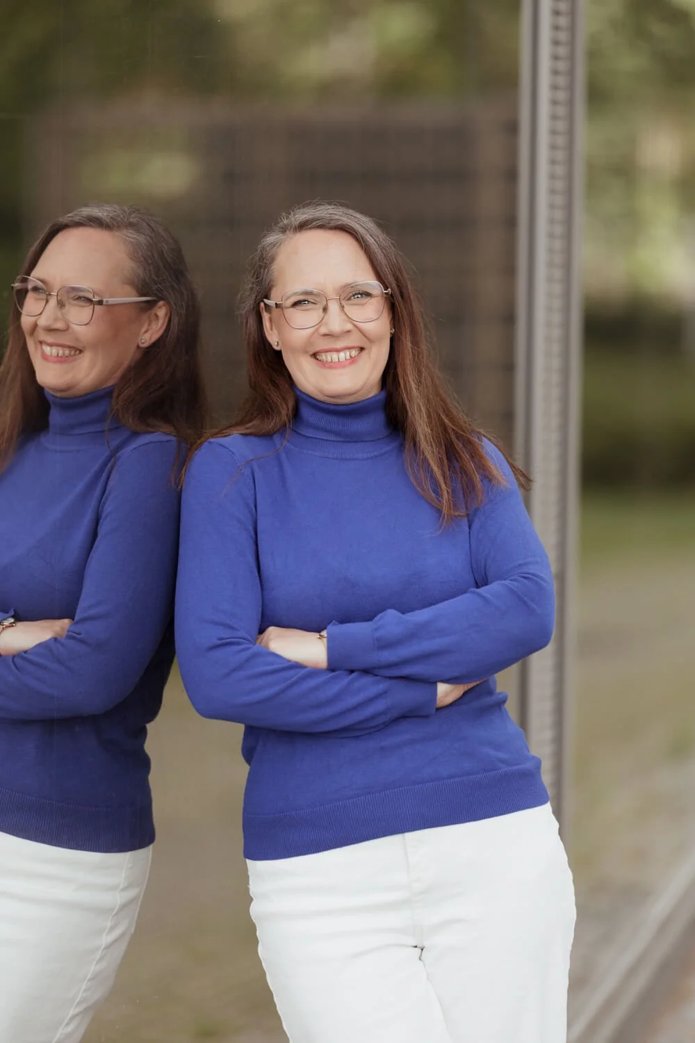 Nainen nojaa lasiseinää vasten ja pinta heijastuu