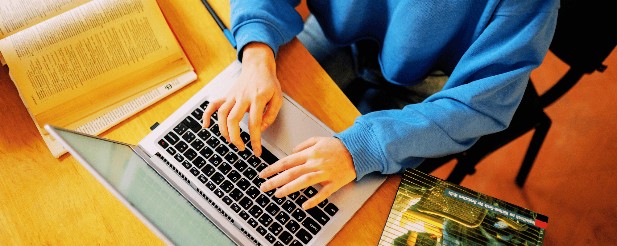 Person researching online discovery on a laptop beside open books.
