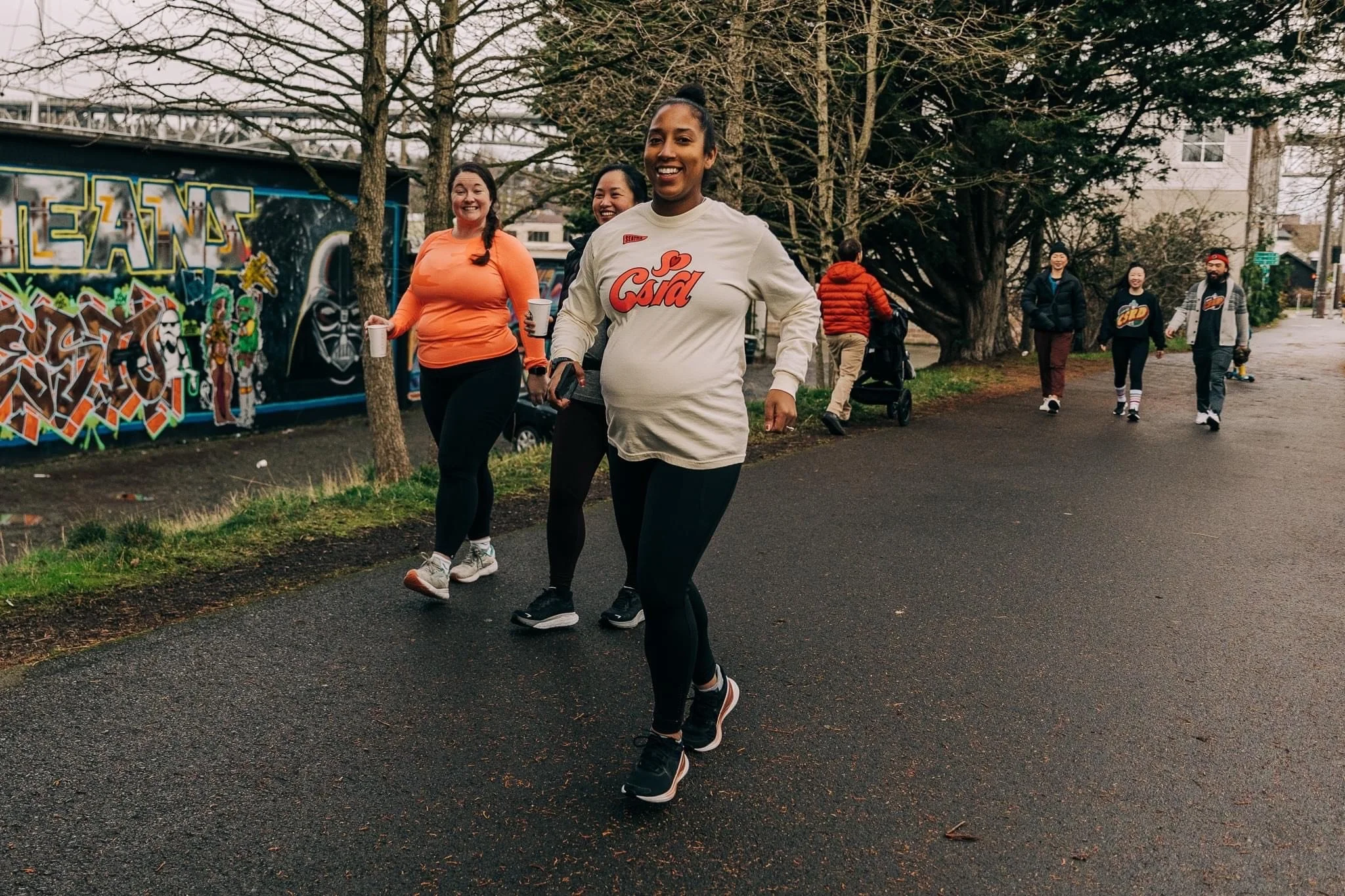 A pregnant person jogs on a city sidewalk