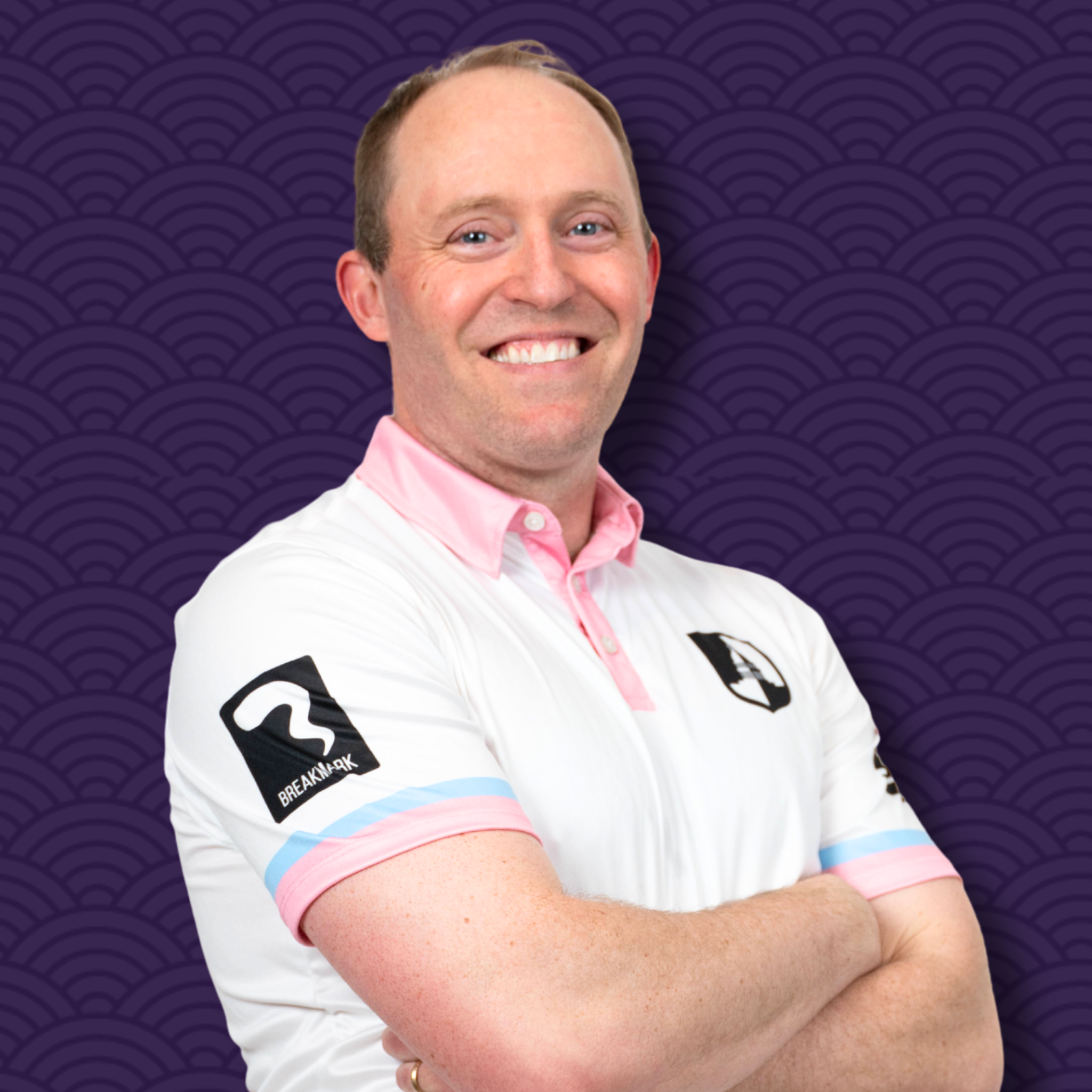A smiling man wearing a white polo shirt with black and pastel pink and blue accents, crossed arms, against a purple textured background.