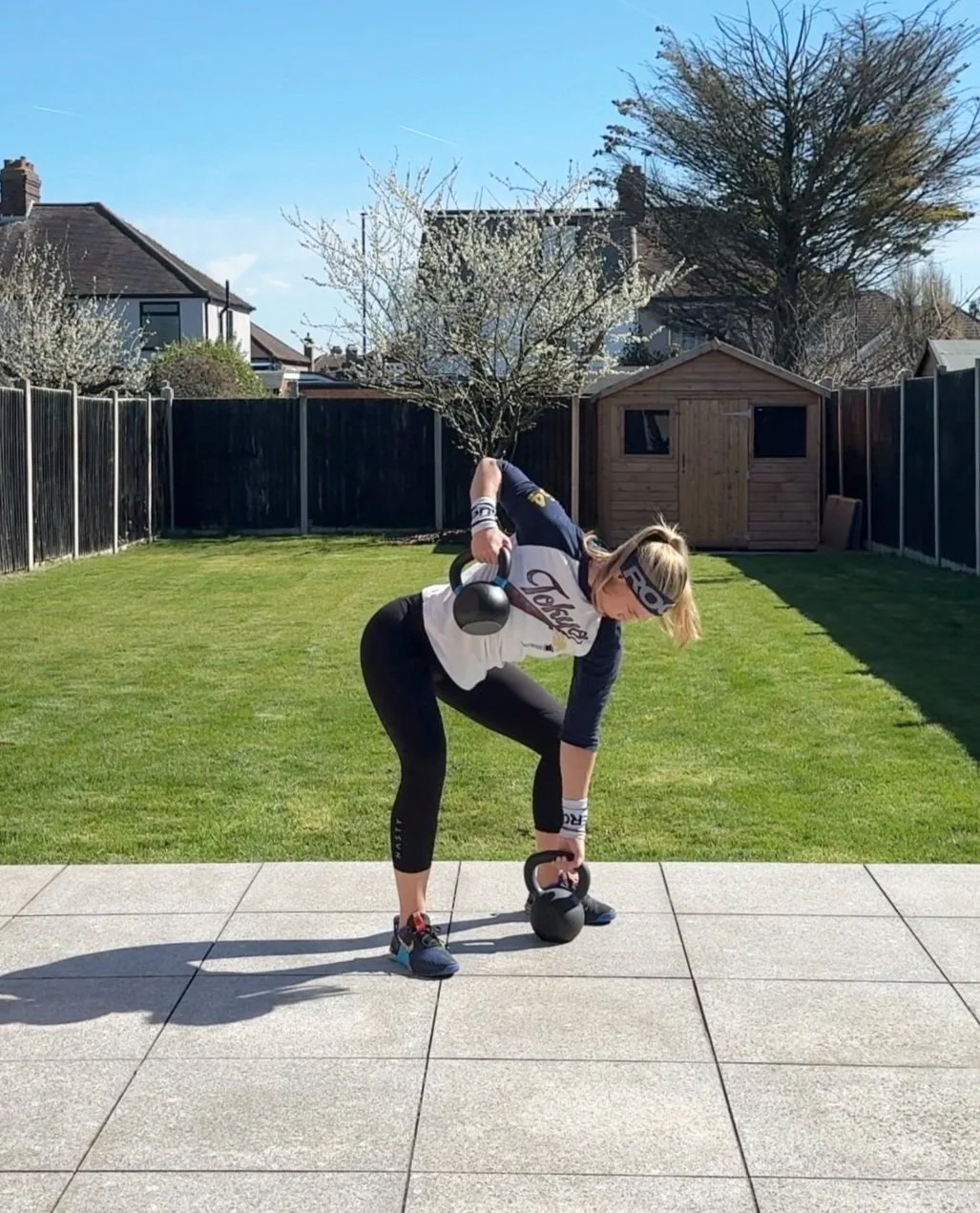 woman is training in her garden using kettlebells