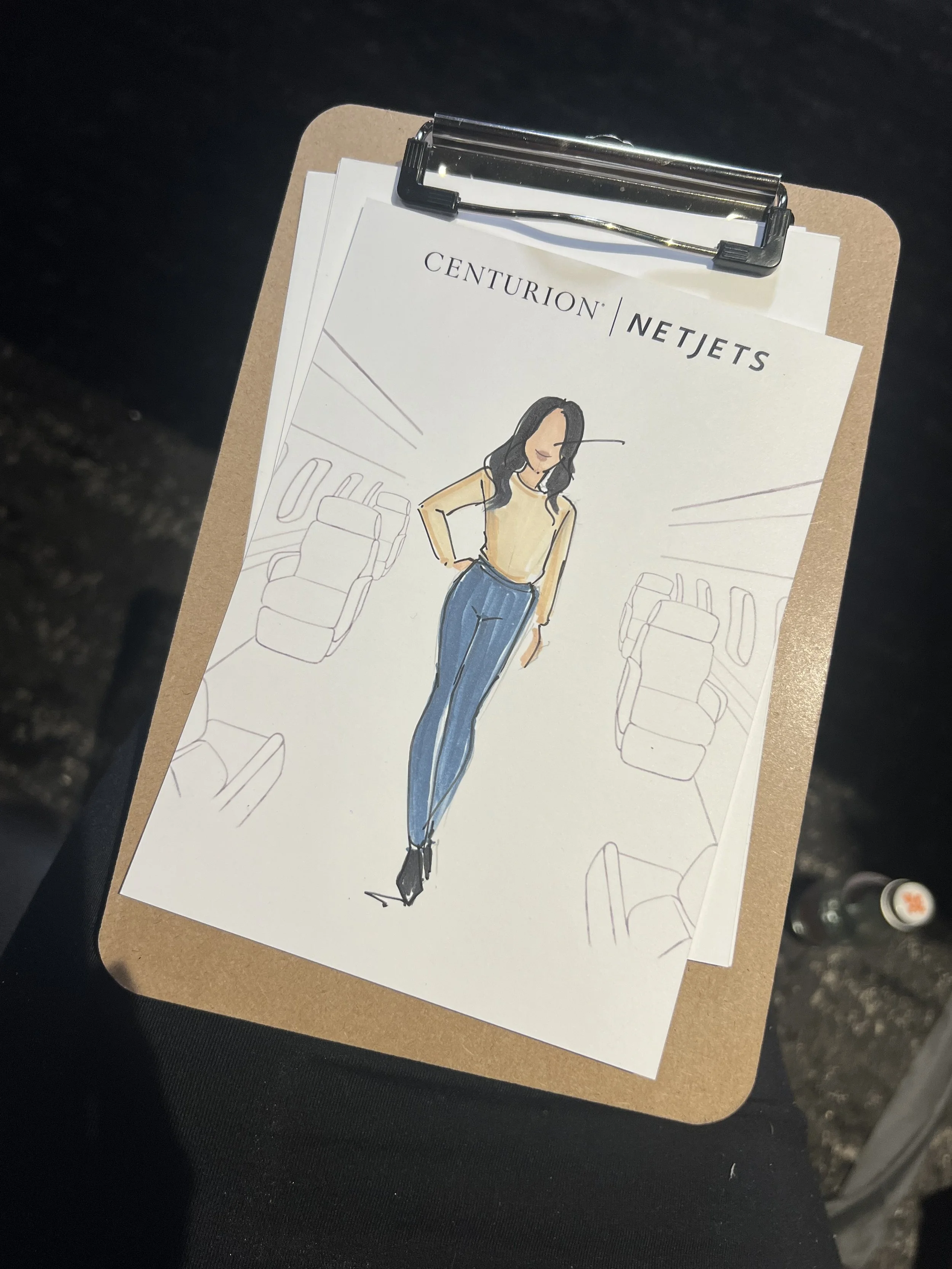 Illustration on clipboard with woman wearing blue jeans and beige top, surrounded by airplane interior sketches, labeled "Centurion | NetJets."