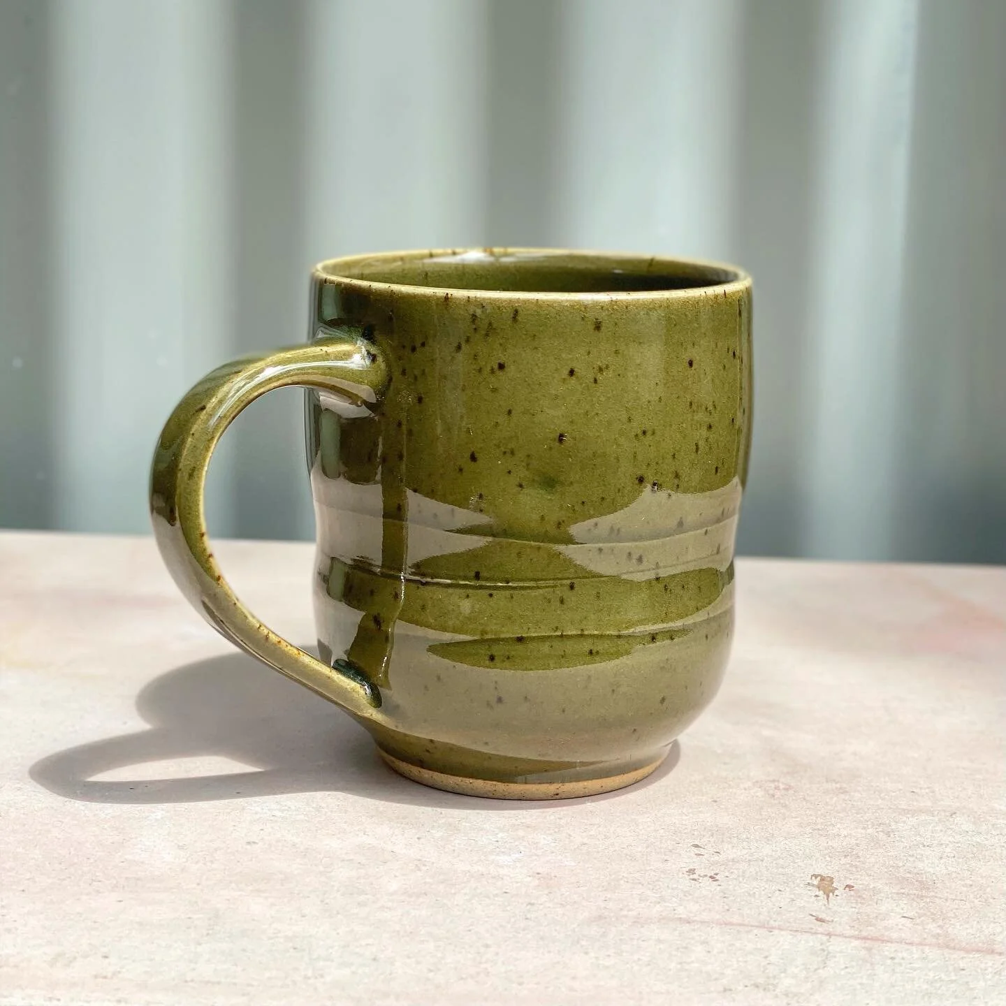 This olive celadon glaze gets its colour from the iron in both the clay and glaze. The dark speckling comes from iron in the clay body that has bled through the glaze due to the reduction fired atmosphere. 🔥I made these mugs in a series and I&rsquo;