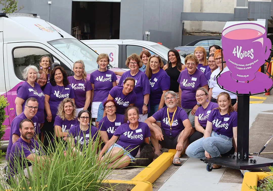 A group of smiling 4 Voices staff and volunteers