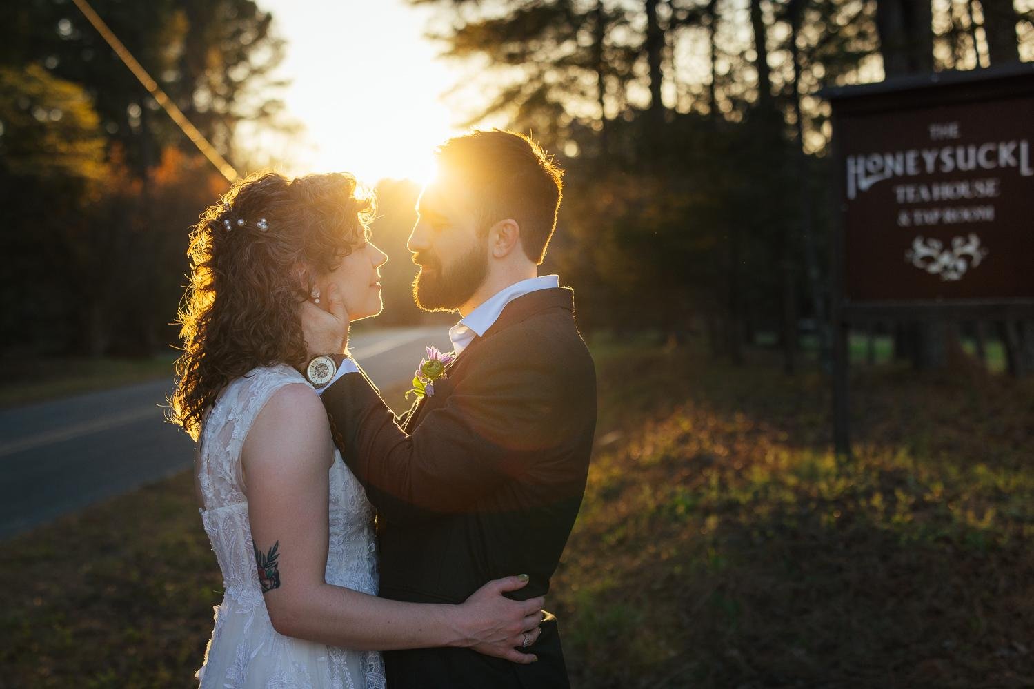 Bride and groom embracing at sunset with the Honeysuckle Tea House sign glowing in the warm golden background — Chapel Hill NC wedding photographer