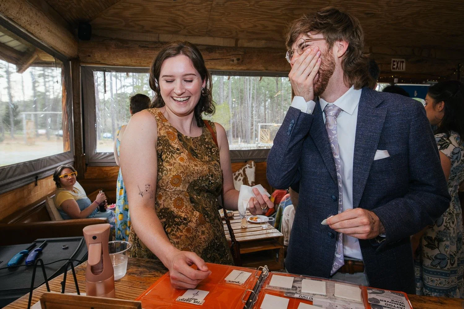 Female wedding guest laughing at the guest book and photo display table inside the reception pavilion at Honeysuckle Tea House Chapel Hill NC
