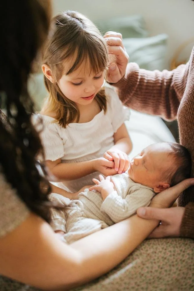Older sibling and parents together for a newborn photoshoot in Durham NC