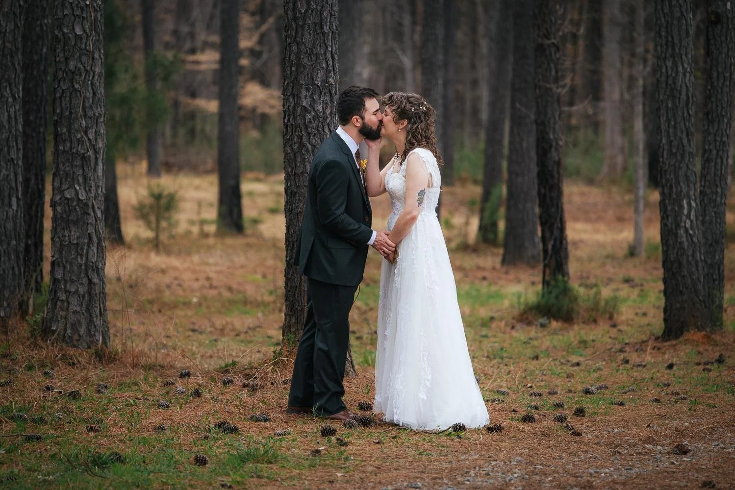 Bride and groom sharing their first kiss together among towering pine trees during their first look at Honeysuckle Tea House wedding in Chapel Hill NC