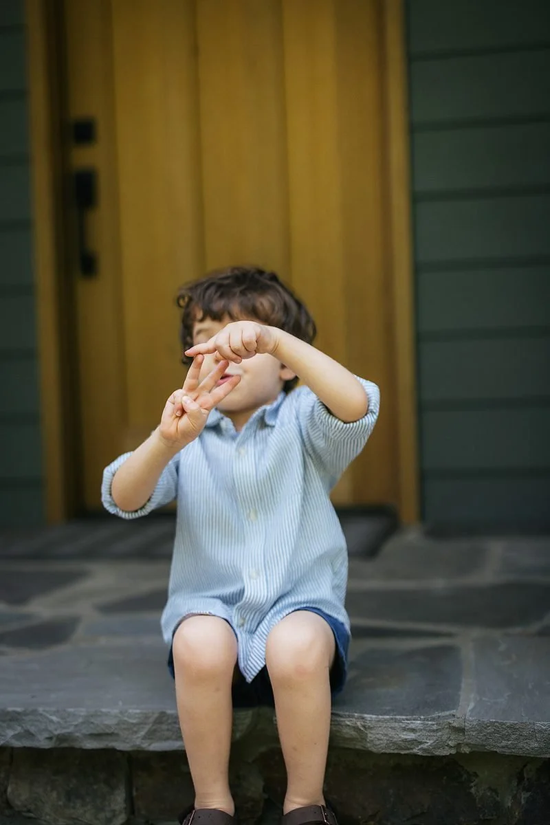 Toddler boy counting his three fingers during family photo session at home