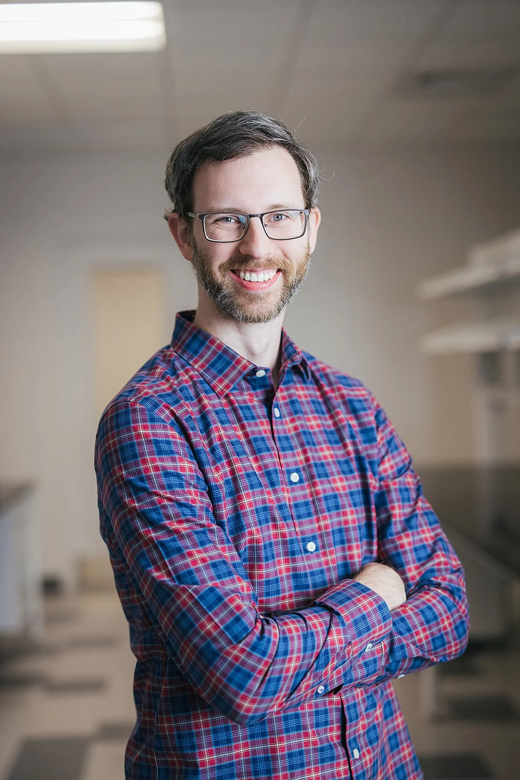 ManInRedAndBluePlaidShirtSmilingArmsCrossed