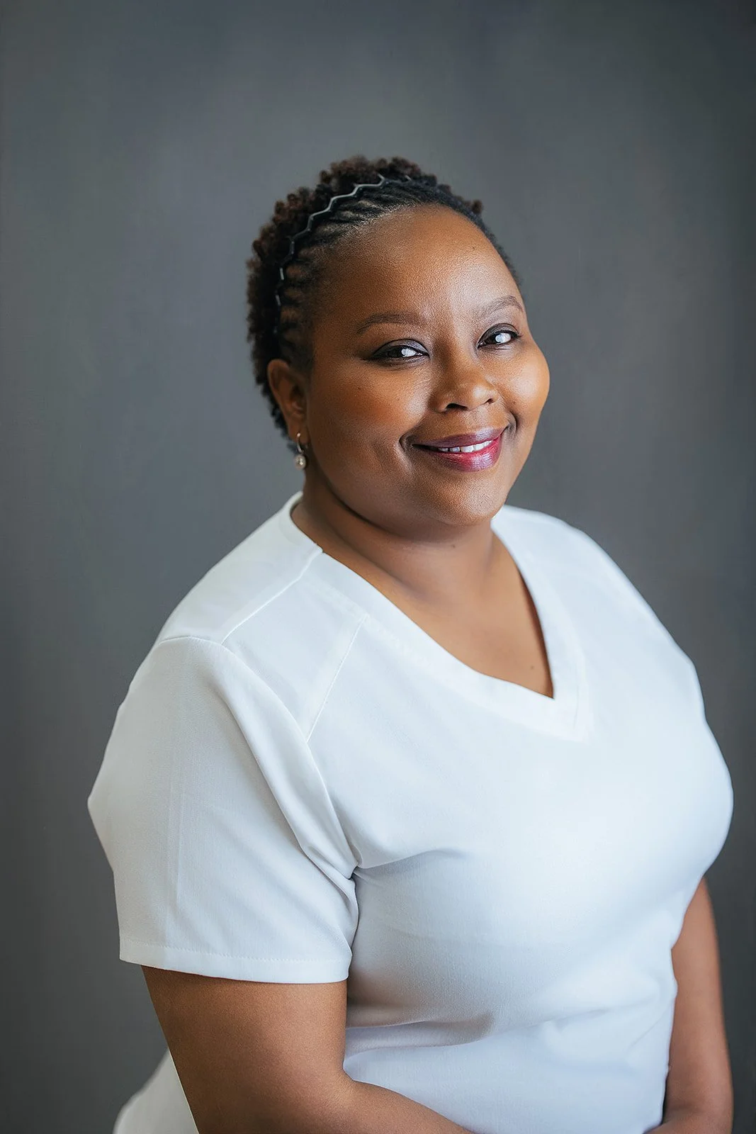 Durham Tech nursing student with braided updo, warm smile in white scrubs, professional headshot by Fifty Two Hundred Photography Durham NC
