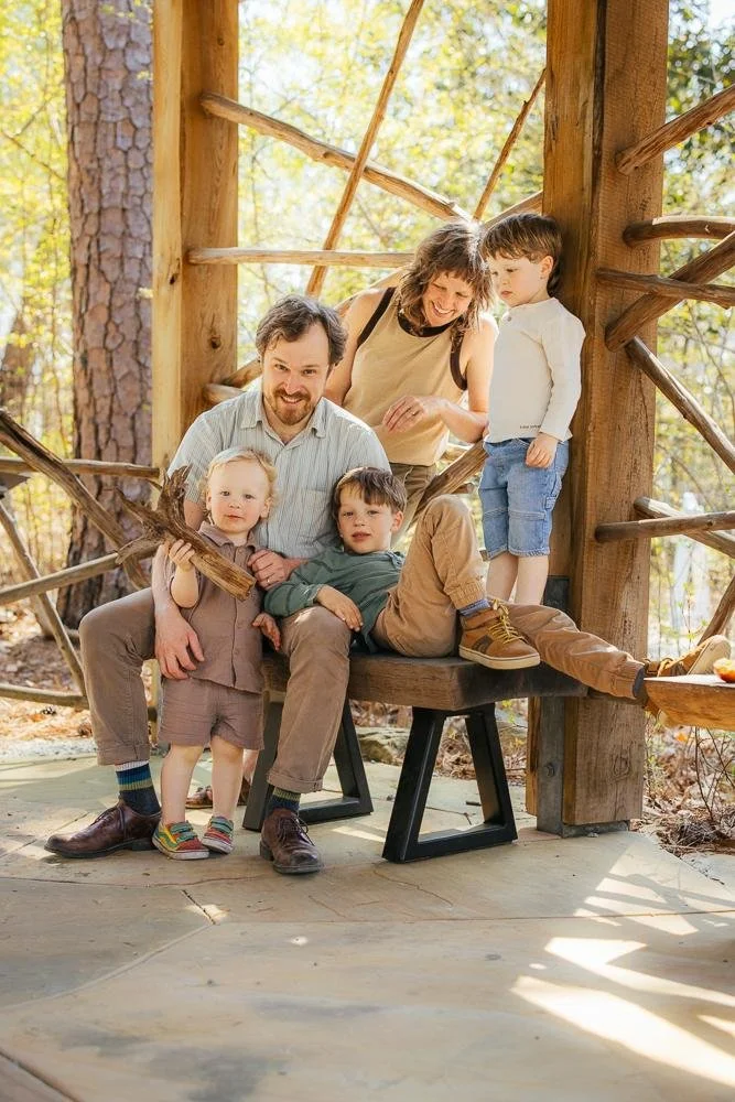 Family of five portrait inside a rustic wooden pergola shelter at Duke Gardens Durham NC — parents and three boys