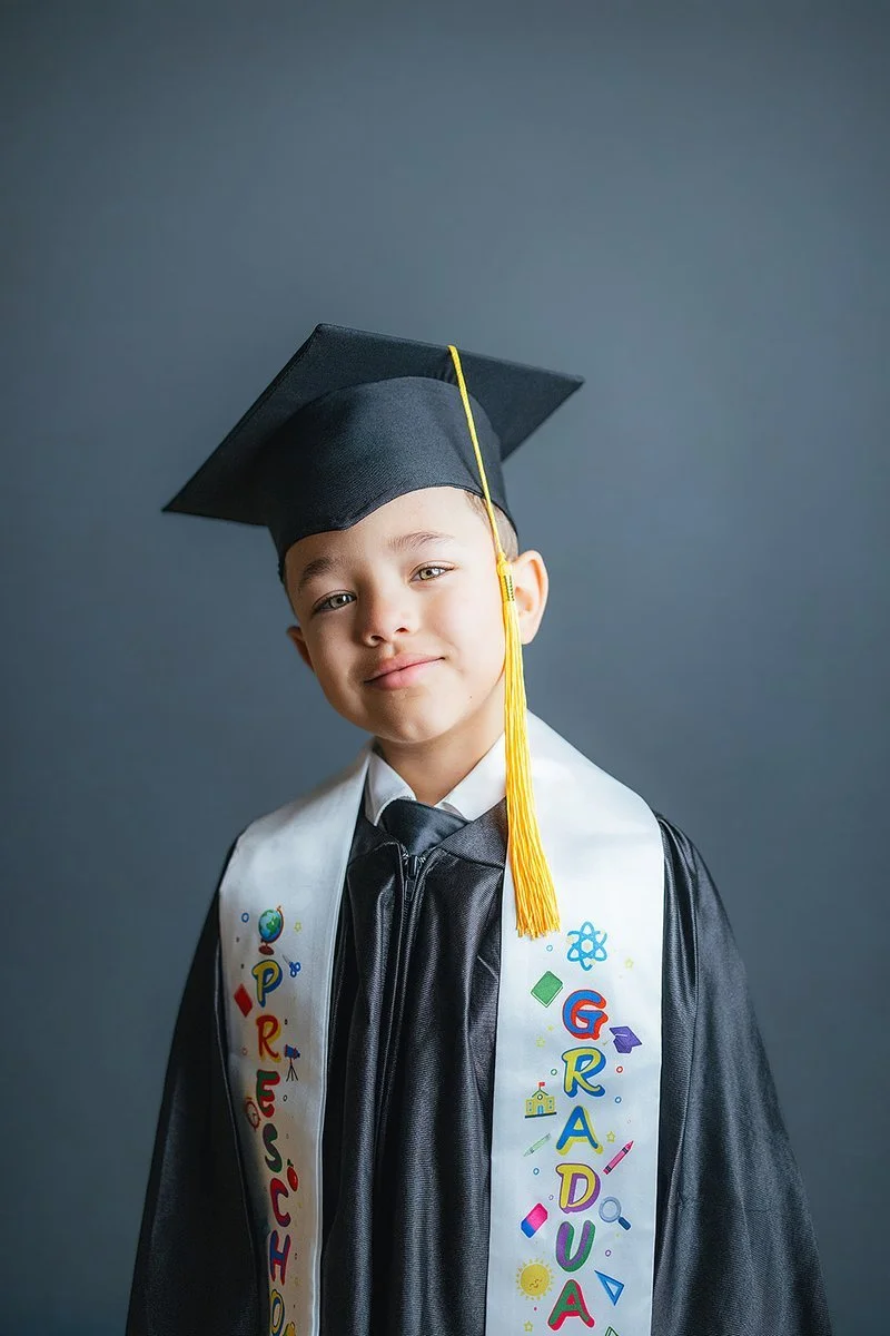Young Boy Smiling At Durham Preschool in Graduation Cap and Gown