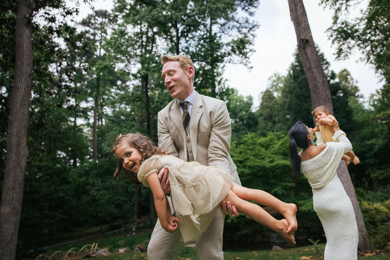 Dad holds one child and mom holds another during a family photoshoot at Duke Gardens in Durham, NC