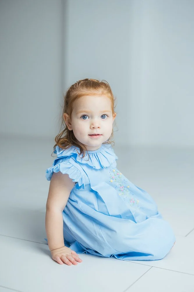 Girl with blue eyes smiles at the camera at a Durham NC milestone portrait photo session