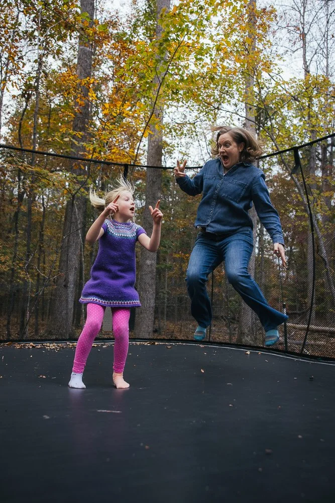 Mom jumping on trampoline with daughter in Durham NC backyard