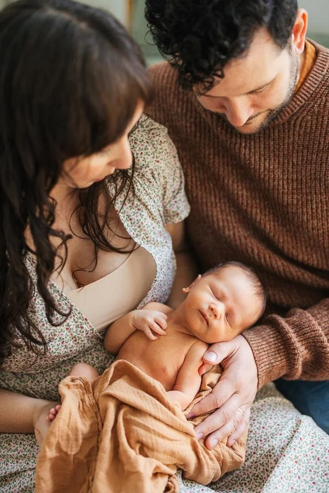 Both parents looking down together at their sleeping newborn baby — intimate couple moment from a Durham NC newborn session