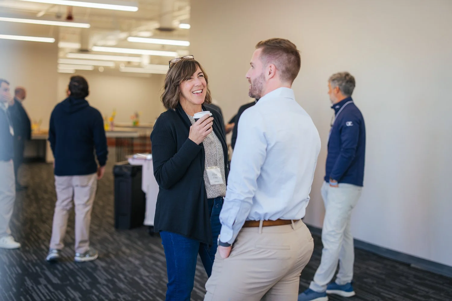 Two attendees laughing together at a corporate networking event at Longfellow Triangle LIFE campus, Raleigh NC, photographed by Triangle corporate event photographer