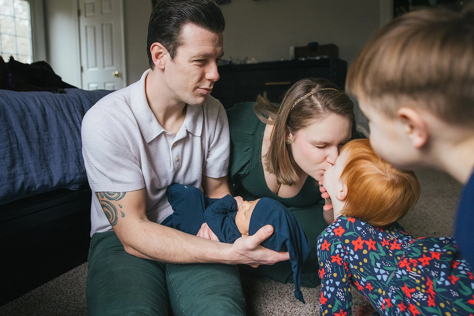 Family gathers around a newborn baby for an in-home newborn photoshoot in Durham, NC