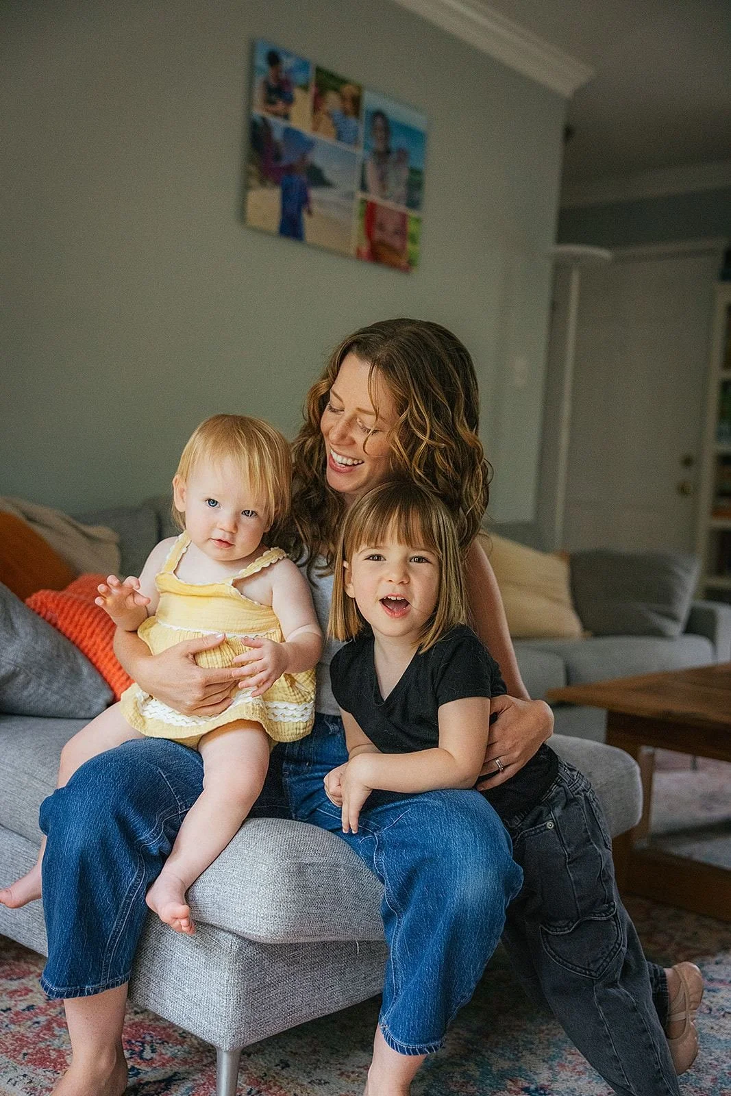 Mom Holding Both Young Girls in Lap Sitting in Living Room