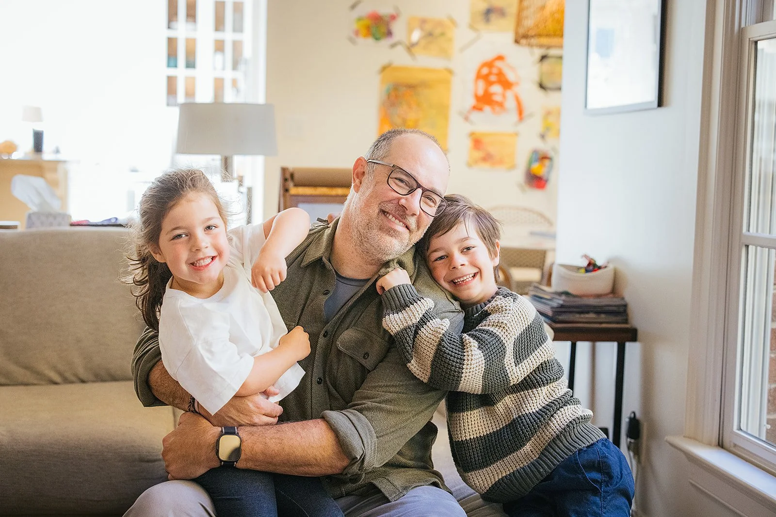 Dad Smiling With Two Young Daughters in Living Room