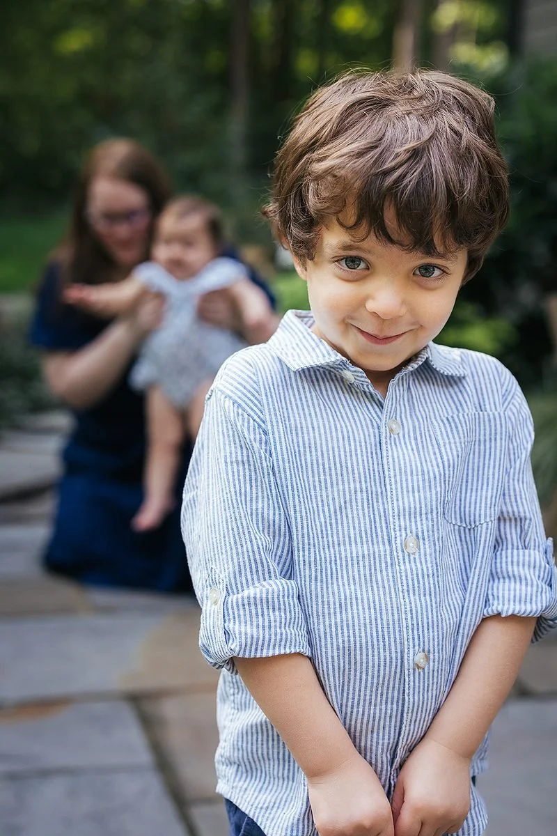 Young boy in blue button down shirt smiling while outside