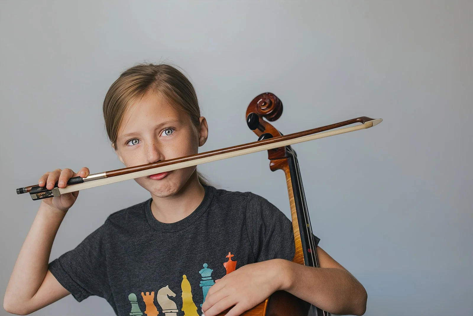 Young Girl Posing with Cello Bow as Mustache in Durham NC Studio Portrait Session