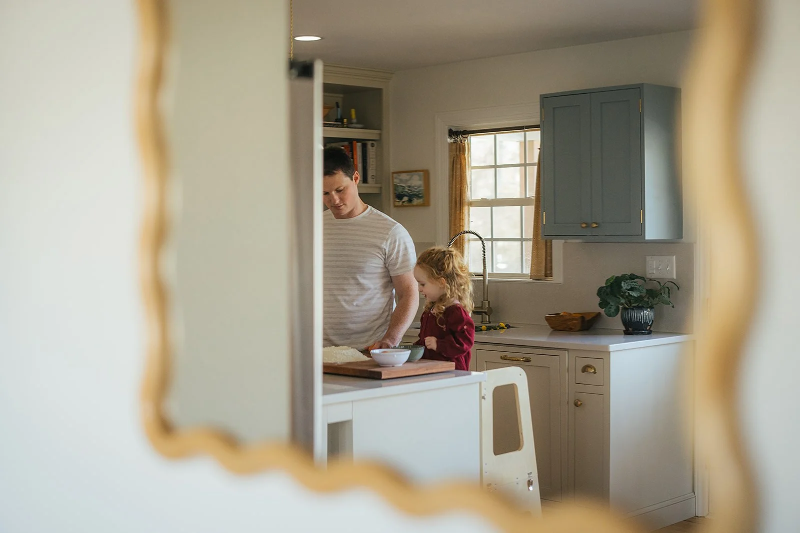 Dad and toddler cooking together in kitchen, captured through mirror reflection by Durham family photographer