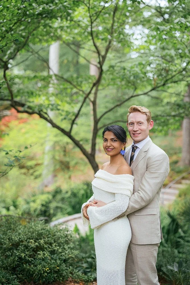 husband hugs wife during vow renewal ceremony at Duke Gardens in Durham, NC