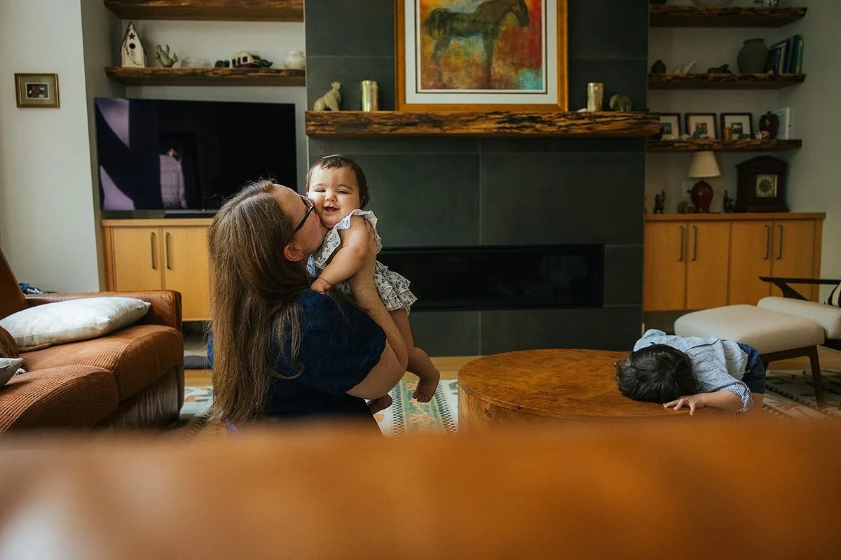 Mom kissing baby's cheek while sitting on living room floor