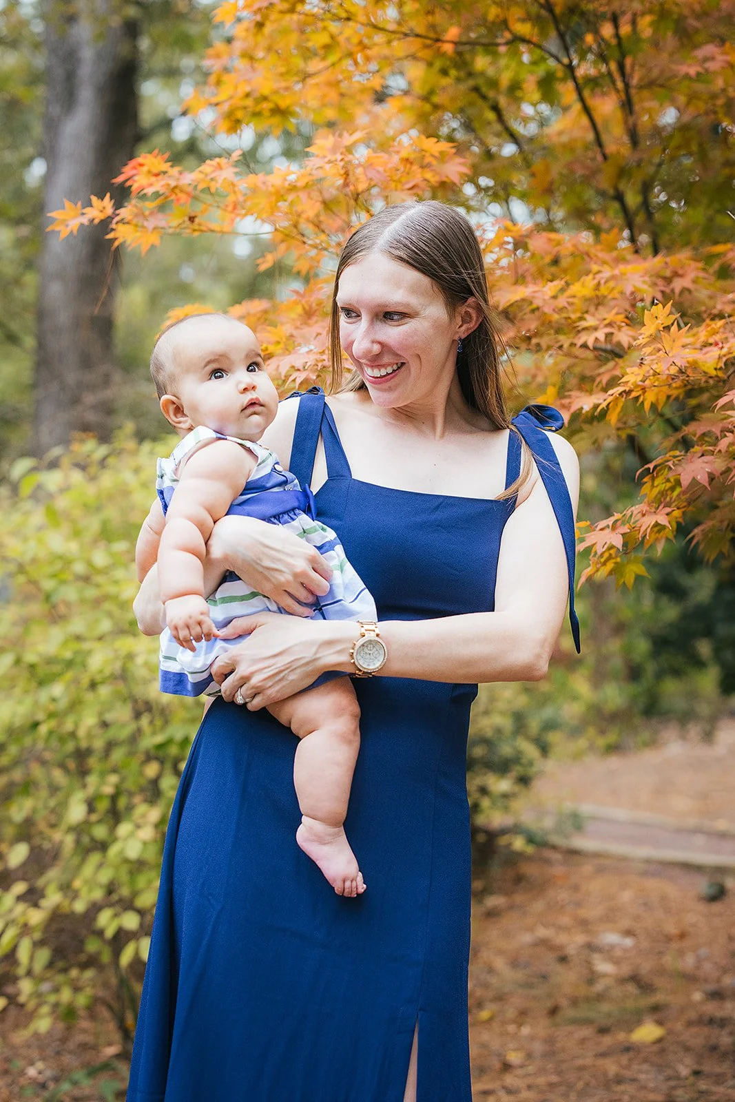 Mom in Bright Blue Dress Holding Baby Among Foliage