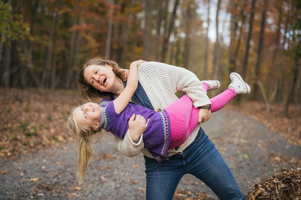 Mom holding and playing with young daughter outside in woods Durham NC