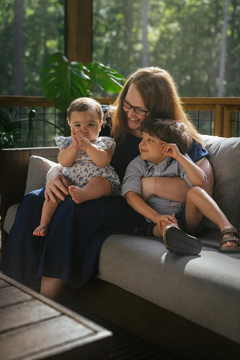 Mom smiling while young baby claps sitting on screened in porch