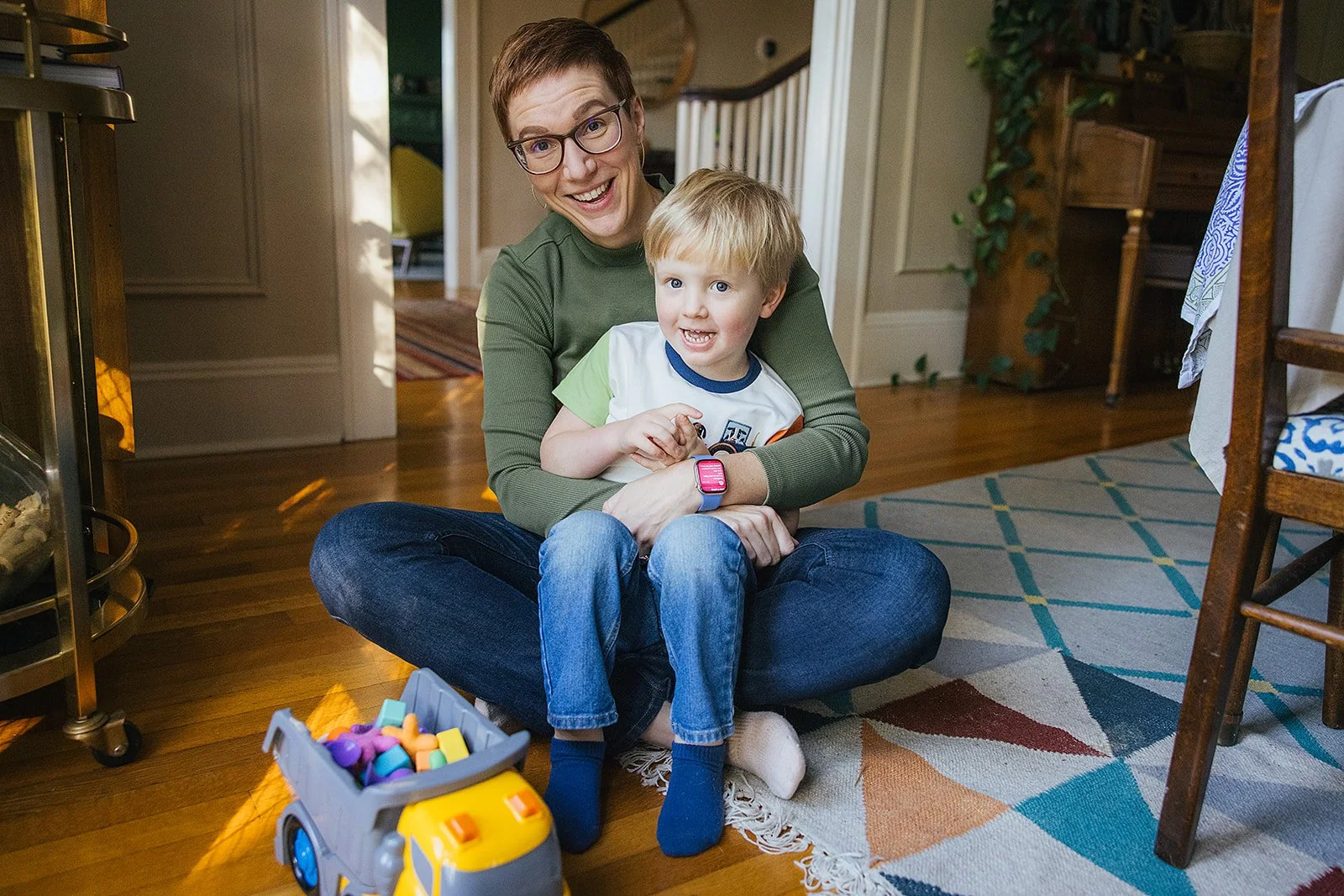 Mom Sitting With Young Son On Living Room Floor During Family Photo Session