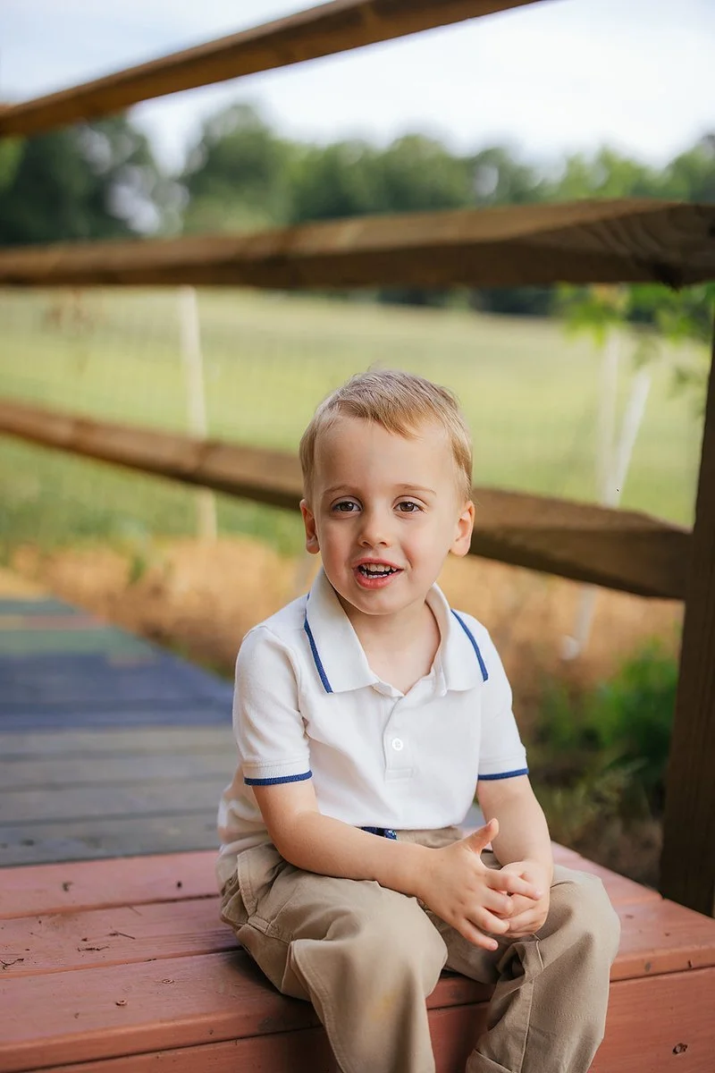 Young Boy Sitting In Front Wooden Fence and Grass, Durham Chapel Hill Photographer
