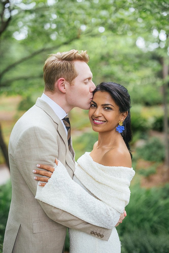 Husband kisses wife's forehead after vow renewal ceremony at Duke Gardens in Durham, NC