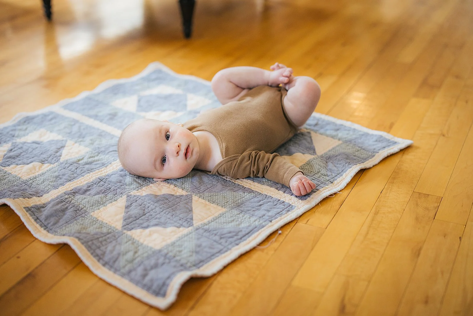 Baby during tummy time on a heirloom quilt on hardwood floors during Durham lifestyle newborn photography session