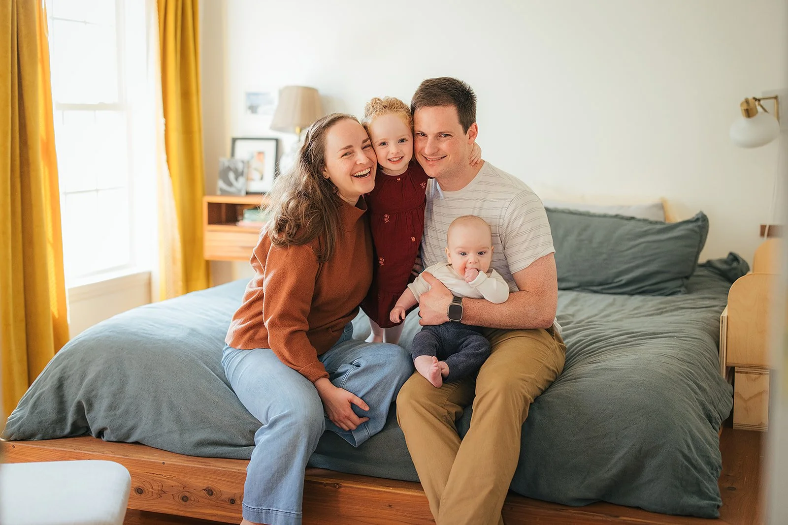 Happy family portrait on bed during Durham in-home lifestyle family photography session with two young children