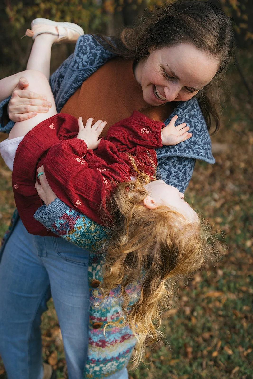 Mom swings laughing toddler daughter upside down outdoors during Durham NC family photography session